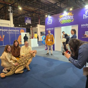 A presidente da Abav Nacional, Ana Carolina Medeiros, com o filhote de dinossauro do Terra dos Dinos, no estande do SINDEPAT